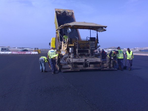 Extendido de aglomerado asfáltico en pista de rodaje y excavación para canalizacón y drenaje